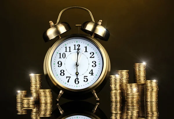 Alarm clock with coins on dark background — Stock Photo, Image