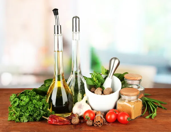 Composition of mortar, bottles with olive oil and vinegar, and green herbals, on bright background — Stock Photo, Image