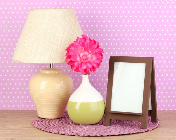 Marco de fotos marrón y lámpara sobre mesa de madera sobre fondo de pared lila — Foto de Stock