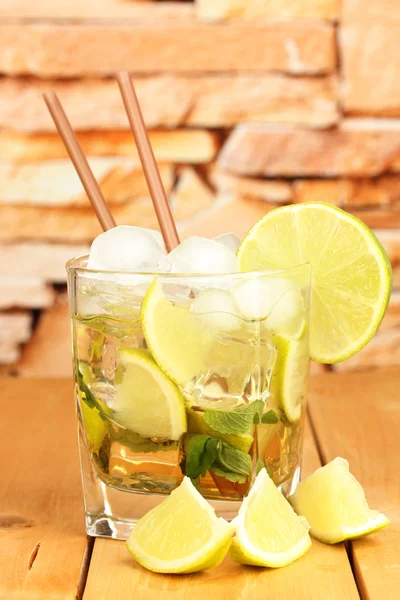 Glass of cocktail with lime and mint on wooden table on bright background — Stock Photo, Image