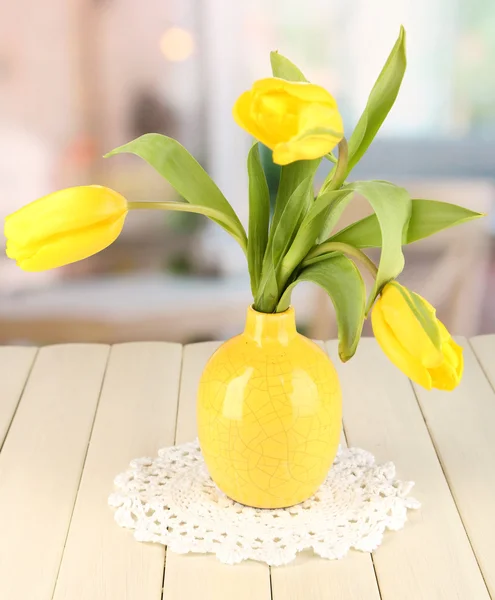 Gelbe Tulpen in Vase auf Holztisch auf Zimmerhintergrund — Stockfoto