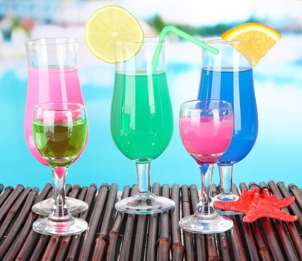 Glasses of cocktails on table near pool — Stock Photo, Image