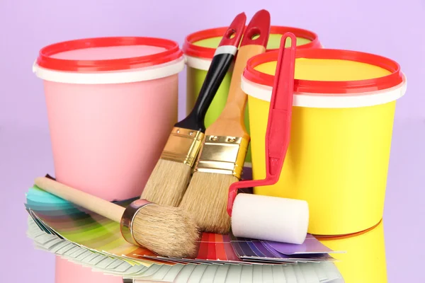 Set for painting: paint pots, brushes, paint-roller, palette of colors on lilac background — Stock Photo, Image