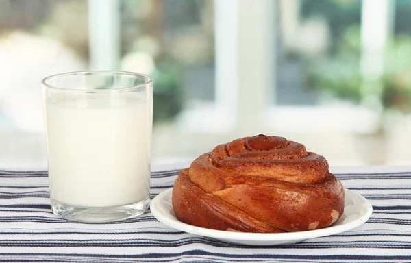 Rollo de pan y vaso de leche sobre fondo de ventana — Foto de Stock