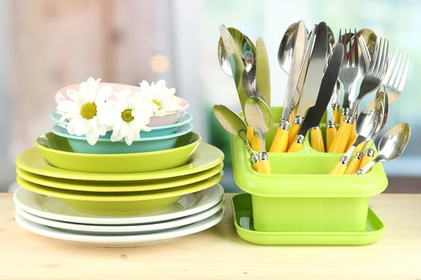 Placas, garfos, facas, colheres e outros utensílios de cozinha sobre fundo brilhante — Fotografia de Stock