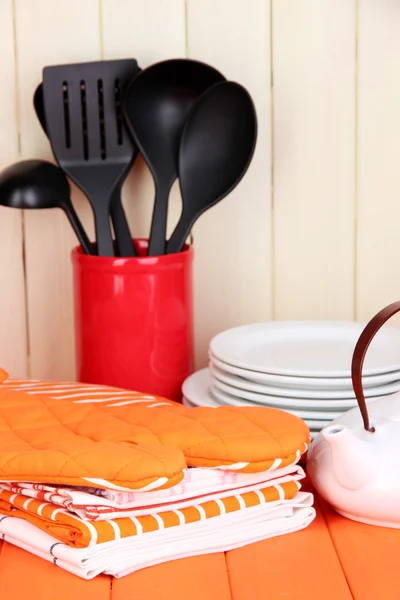 Kitchen settings: utensil, potholders, towels and else on wooden table — Stock Photo, Image