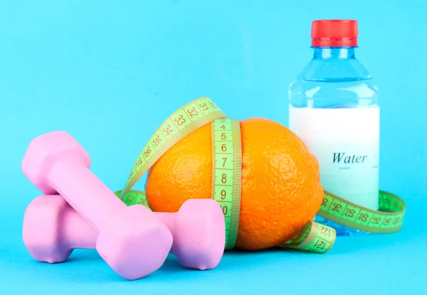 Orange med mätning av tejp, hantlar och en flaska vatten på Cologne bakgrunden — Stockfoto