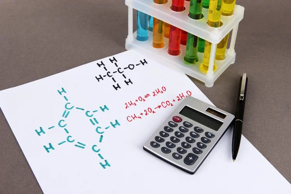 Тестовые трубки с красочными жидкостями и формулами на сером фоне — стоковое фото