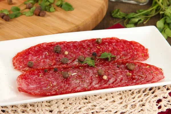 Tasty salami on plate on wooden table close-up — Stock Photo, Image