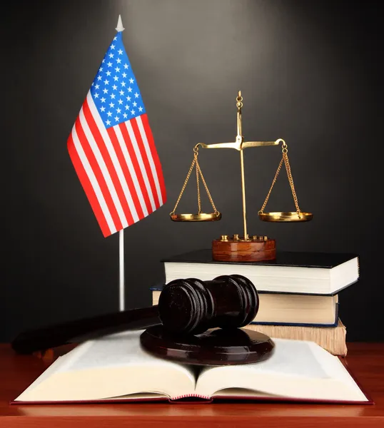 Wooden gavel, golden scales of justice and books on grey background — Stock Photo, Image