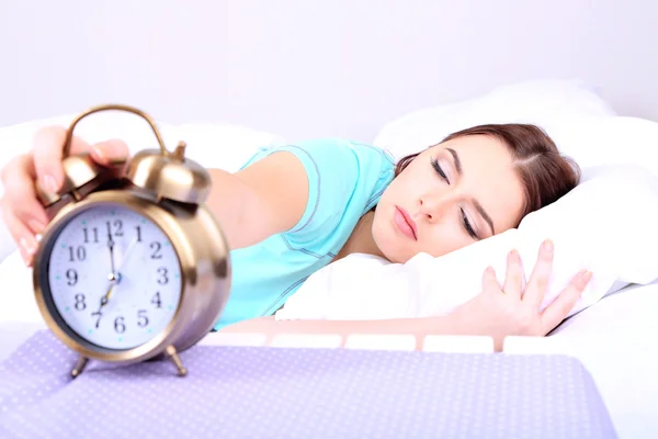 Beautiful young woman sleeping on bed with alarm clock in bedroom — Stock Photo, Image