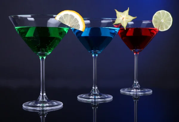 Coquetéis alcoólicos em copos de martini no fundo azul escuro — Fotografia de Stock