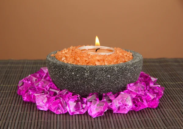 Candle in stone bowl with marine salt, on bamboo mat, on brown background — Stock Photo, Image