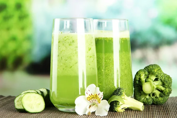 Bicchieri di succo vegetale, su tappetino di bambù, su fondo verde — Foto Stock