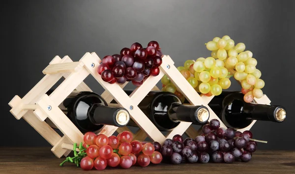 Bouteilles de vin placées sur un support en bois sur fond gris — Photo