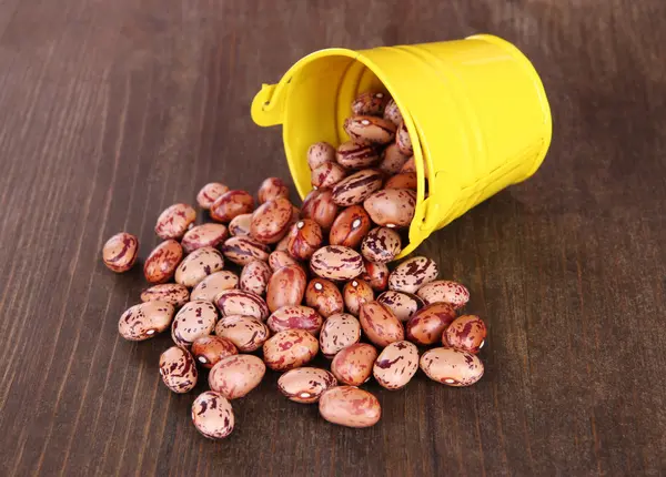 Overturned bucket with beans on wooden background — Stock Photo, Image