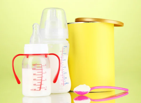 Flessen met melk en voedsel voor baby's op groene achtergrond — Stockfoto