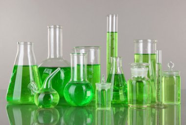 gri zemin üzerine yeşil sıvı ile test tüpleri