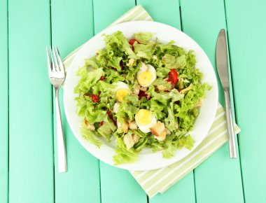 renkli ahşap zemin üzerinde beyaz tabakta Sezar salatası