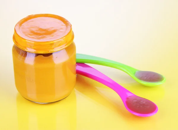 Baby food with weaning spoons on yellow background — Stock Photo, Image