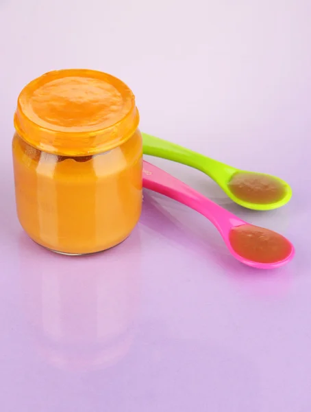Baby food with weaning spoons on purple background — Stock Photo, Image