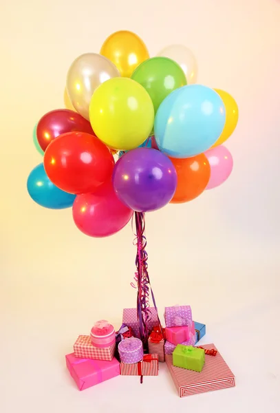 Many bright balloons and many gifts on light background — Stock Photo, Image