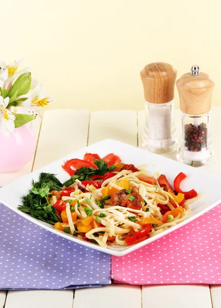 Noodles with vegetables in plate on wooden table — Stock Photo, Image