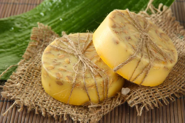 Handgemaakte zeep en blad op grijs bamboe mat — Stockfoto