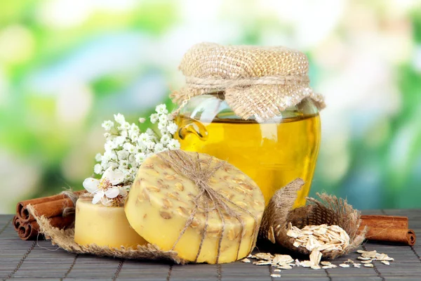 Hand made soap and ingredients for soap making on bamboo mat, on green background — Stock Photo, Image