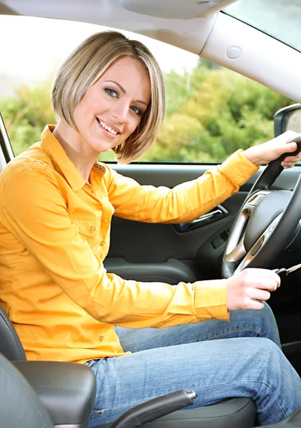 Portrait of young beautiful woman with key sitting in the car — Stock Photo, Image