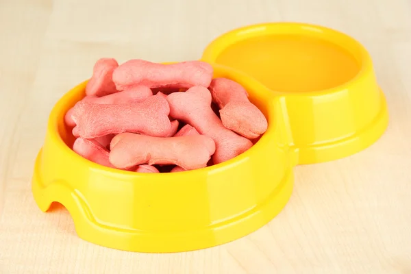 Comida seca para perros en un tazón sobre fondo de madera — Foto de Stock