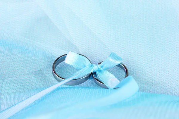Обручальные кольца, связанные лентой на фоне ткани — стоковое фото