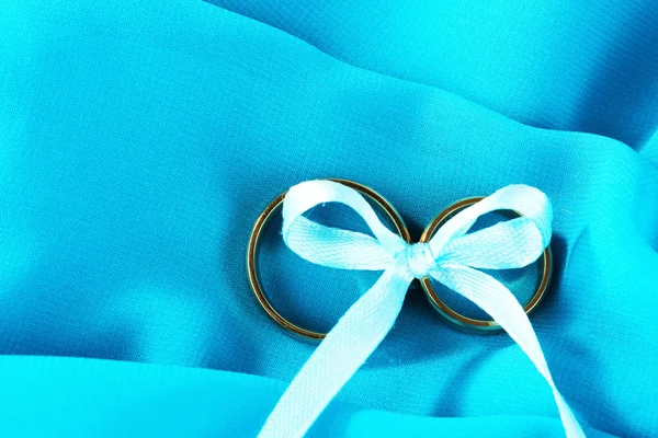 Anéis de casamento amarrado com fita no pano de fundo — Fotografia de Stock