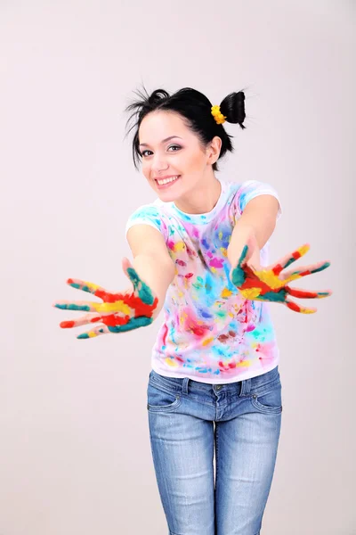 Junge hübsche Malerin mit Händen in Farbe, auf grauem Hintergrund — Stockfoto