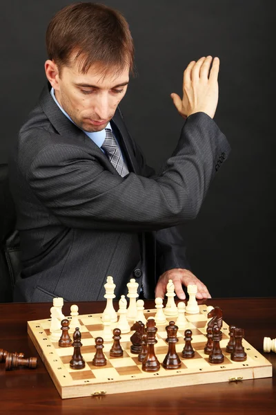 Young business man playing chess on black background — Stock Photo, Image