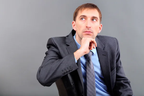 Young businessman on grey background — Stock Photo, Image