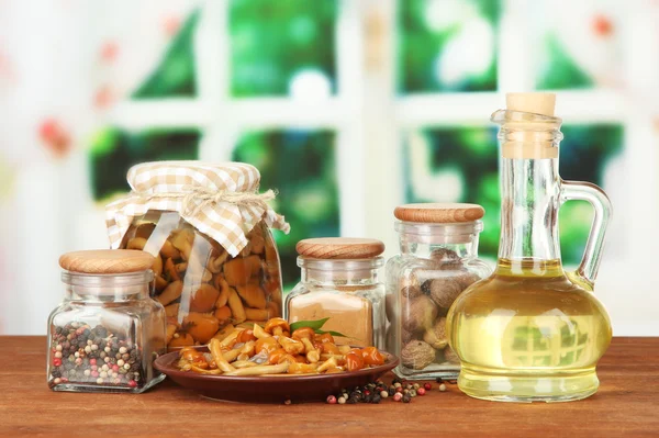 Composition of delicious marinated mushrooms, oil and spices on wooden table on bright background — Stock Photo, Image