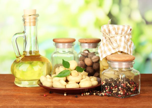 Composición de deliciosos champiñones marinados, aceite y especias sobre mesa de madera sobre fondo brillante —  Fotos de Stock