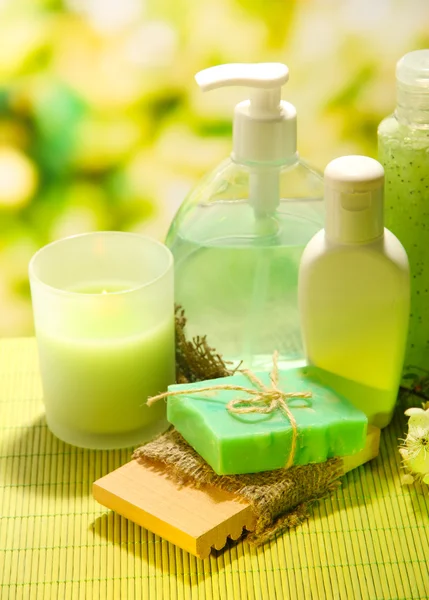 Kozmetikai palackok és természetes kézzel készített szappan, zöld háttér — Stock Fotó