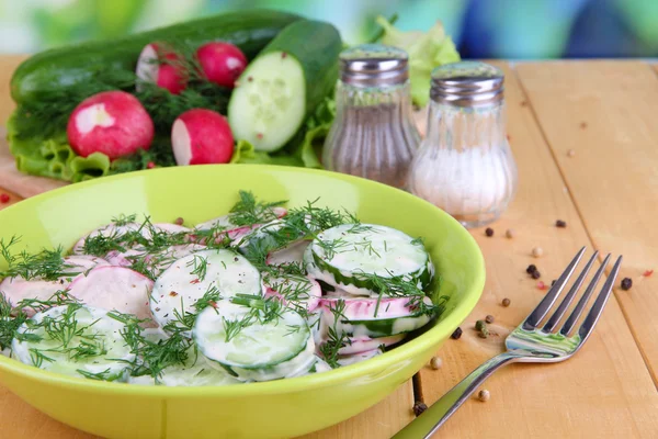 Vitamine plantaardige salade in kom op houten tafel op natuurlijke achtergrond — Stockfoto