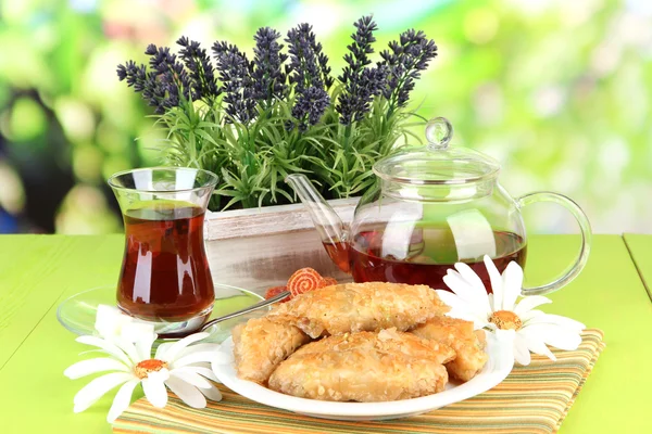 Baklava dulce en el plato con té en la mesa sobre fondo brillante —  Fotos de Stock