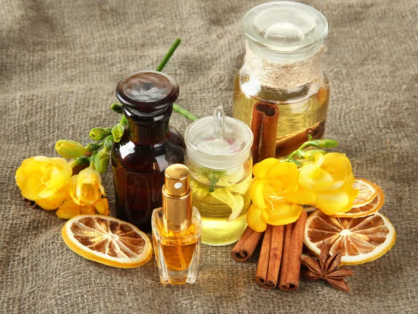 Бутылки с ингредиентами для парфюмерии на фоне мешковины — стоковое фото
