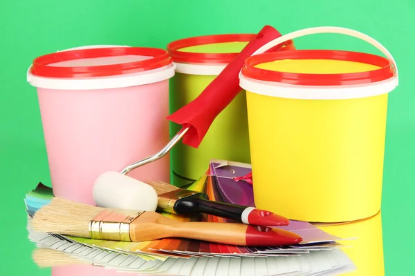 Conjunto para pintura: vasos de tinta, pincéis, rolo de pintura, paleta de cores sobre fundo verde — Fotografia de Stock