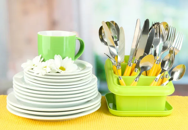 Piatti, forchette, coltelli, cucchiai e altri utensili da cucina su tovagliolo di colore, su sfondo brillante — Foto Stock