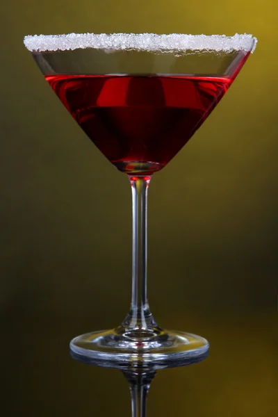 Red cocktail in martini glass on dark yellow background — Stock Photo, Image