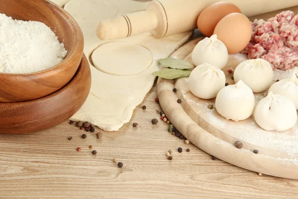 Raw dumplings, ingredients and dough, on wooden table — Stock Photo, Image