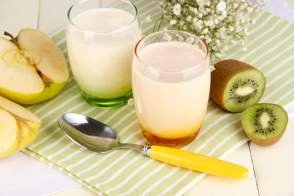 Delicious yogurts with fruits in glasses on wooden table close-up — Stock Photo, Image