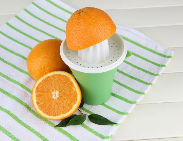 Wyciskarka do cytrusów i dojrzałych pomarańczy na biały drewniany stół — Zdjęcie stockowe