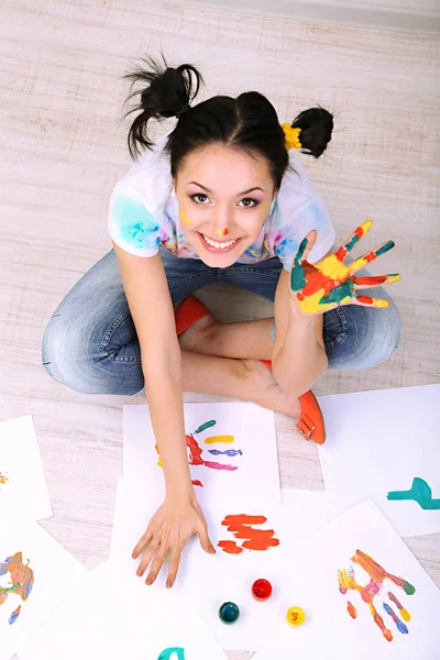 Young pretty painter with hands in paint, on gray background — Stock Photo, Image