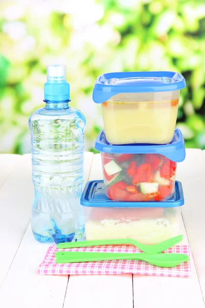 Smakelijke lunch in plastic verpakkingen, op houten tafel op lichte achtergrond — Stockfoto